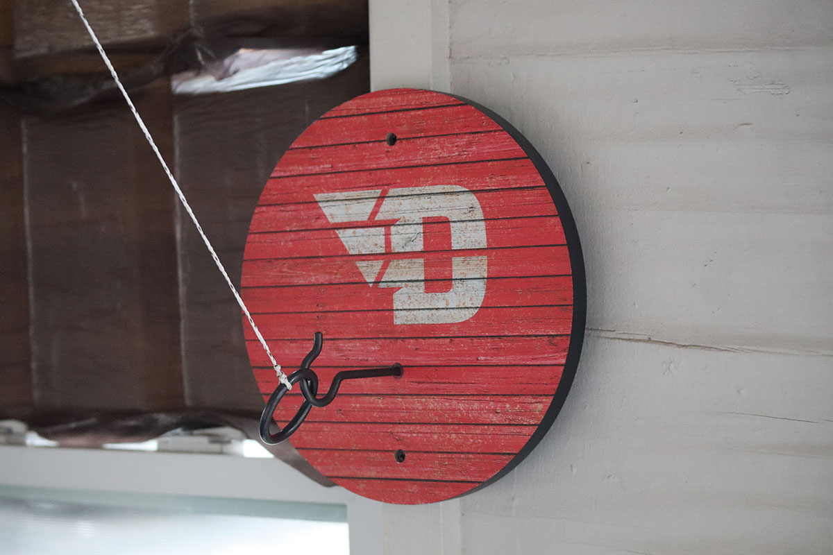 A UD ring toss game hangs on the wall of the back porch of the house.