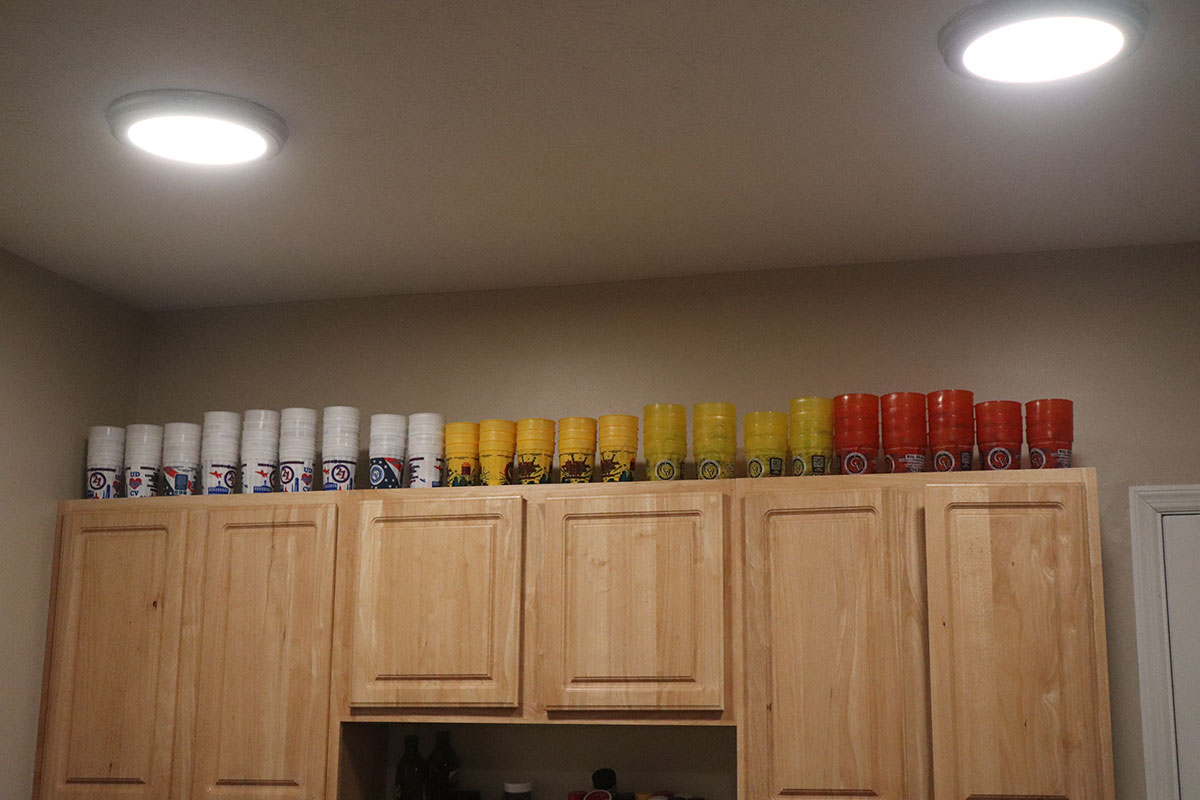 A huge stack of plastic cups sit atop kitchen cabinets,