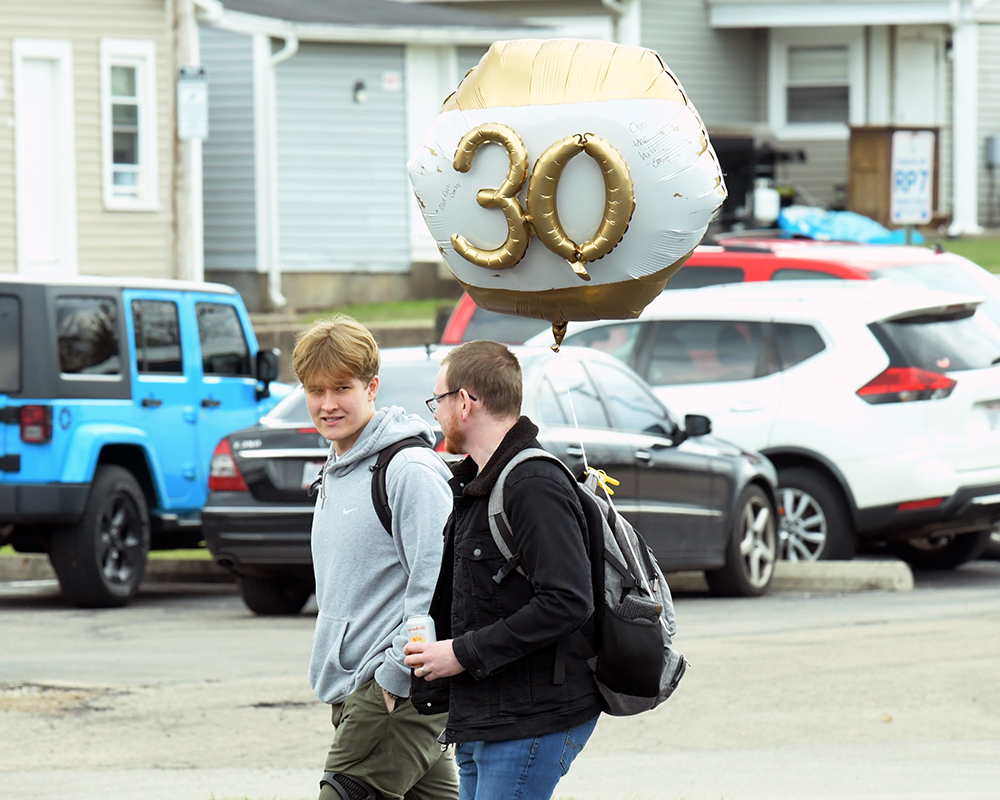 Two people walk carrying a birthday balloon