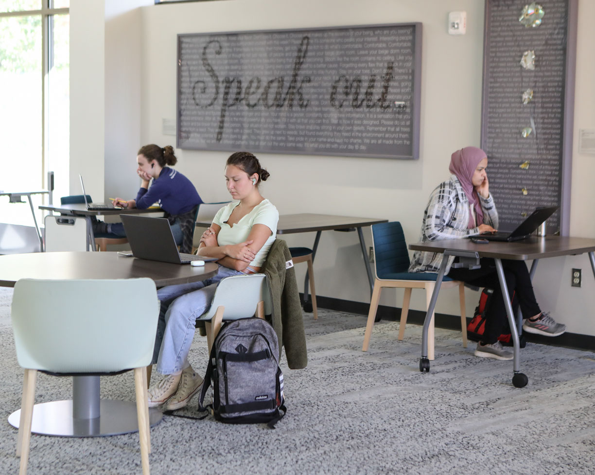 Three students study independently on the first floor of Roesch