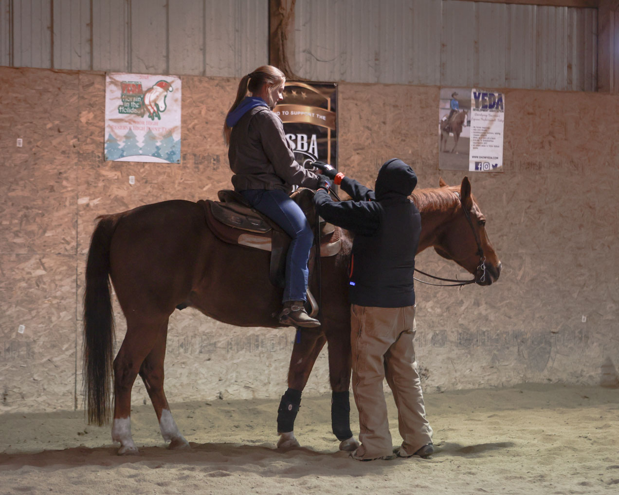 A student sits on a horse while a coach offers corrections