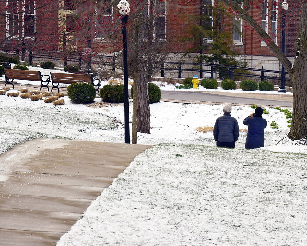 Two people walk across a snowy campus