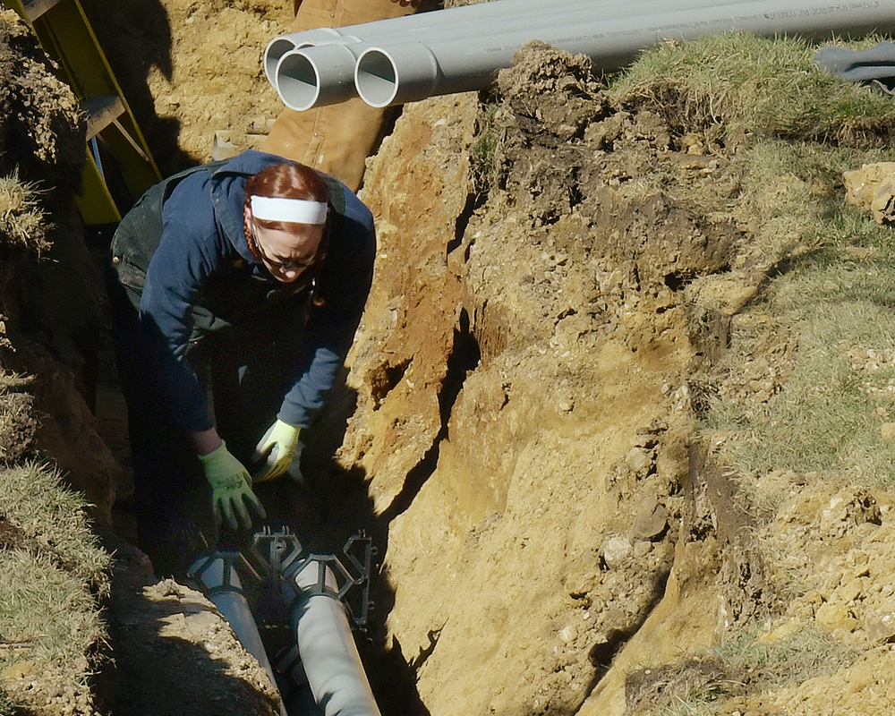 A worker installs underground pipe