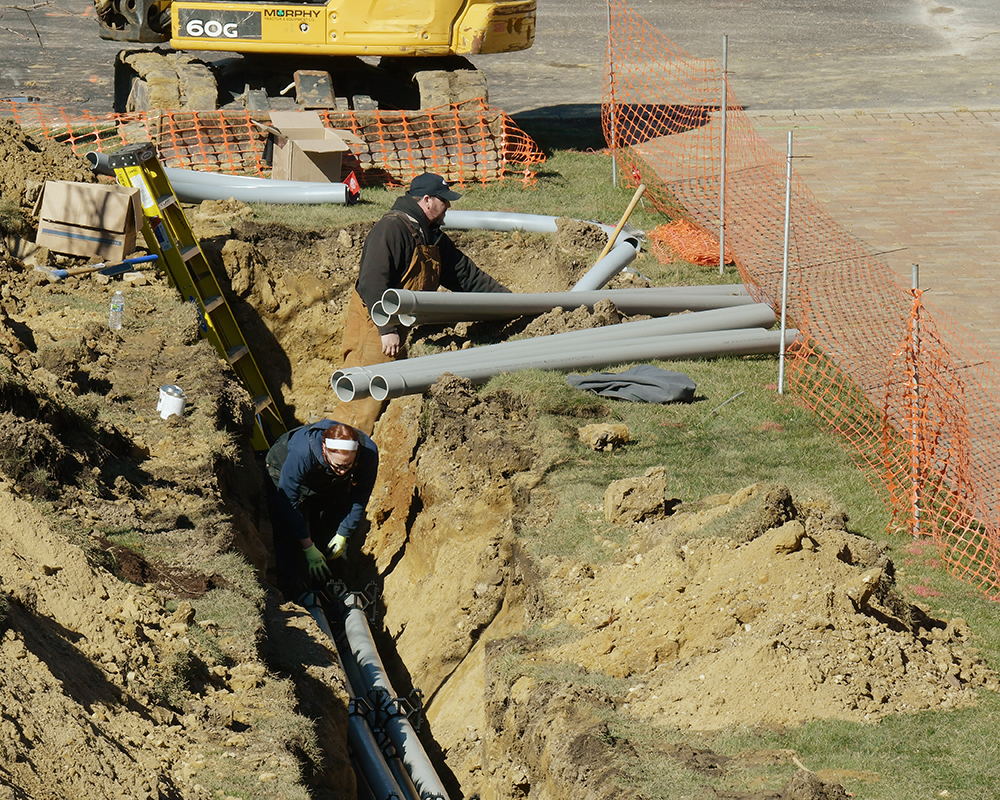 A worker installs underground pipe