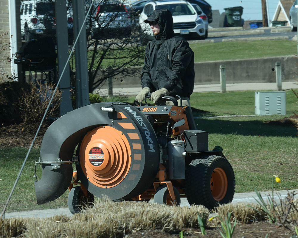 A grounds worker uses an industrial blower