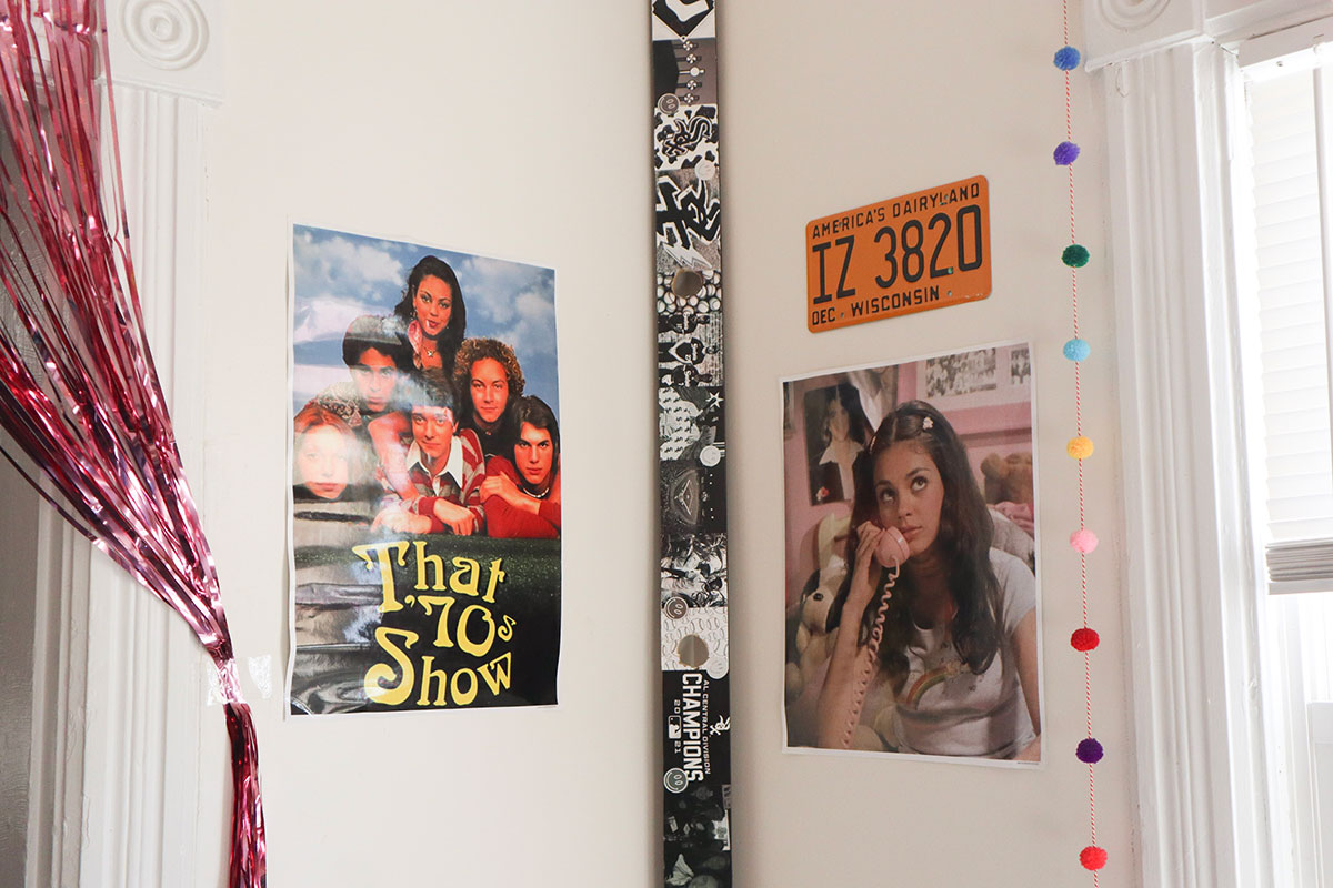 "That 70s Show" posters and a license plate from the show hanging on the walls in a corner.