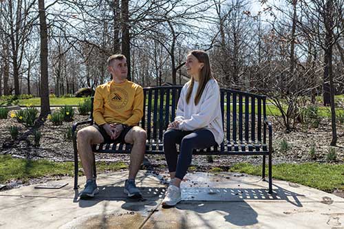 Ben and his sister Kathryn sitting on a park bench together.