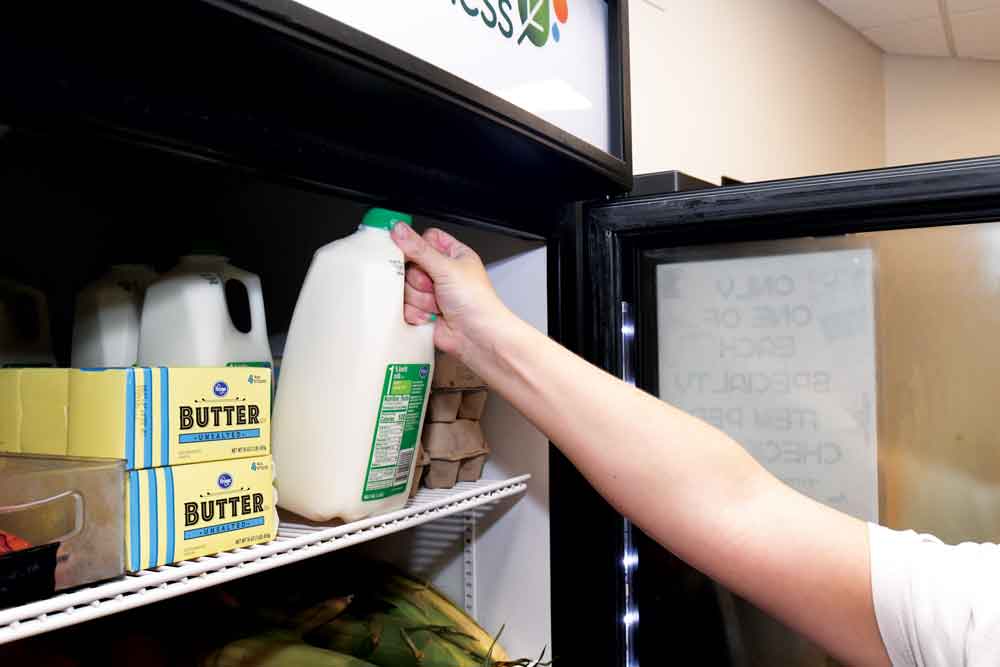Student reaches for a gallon of milk on the shelf.