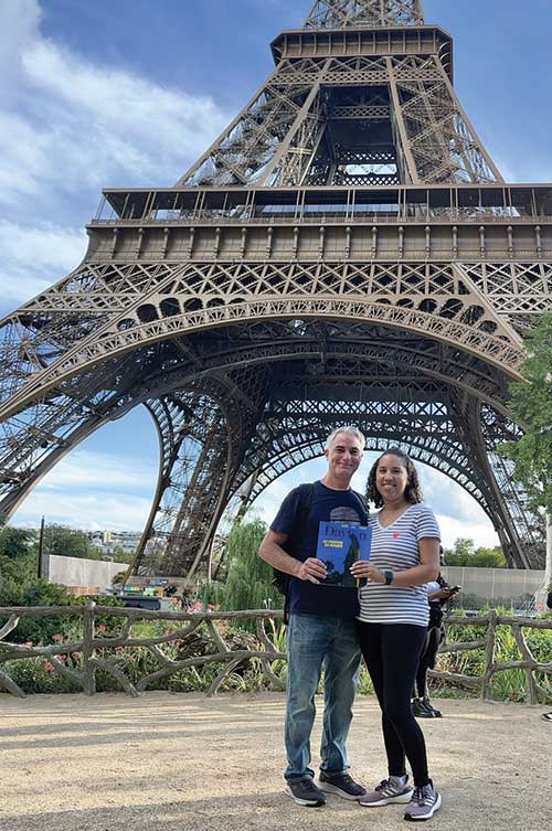 Alumni couple poses at the base of the Eiffel Tower
