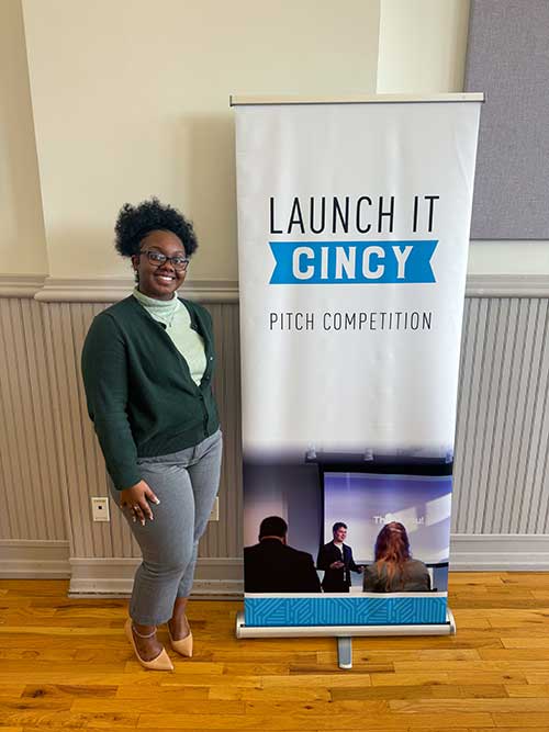Alayah stands next to a sign that reads Launch It: Cincy