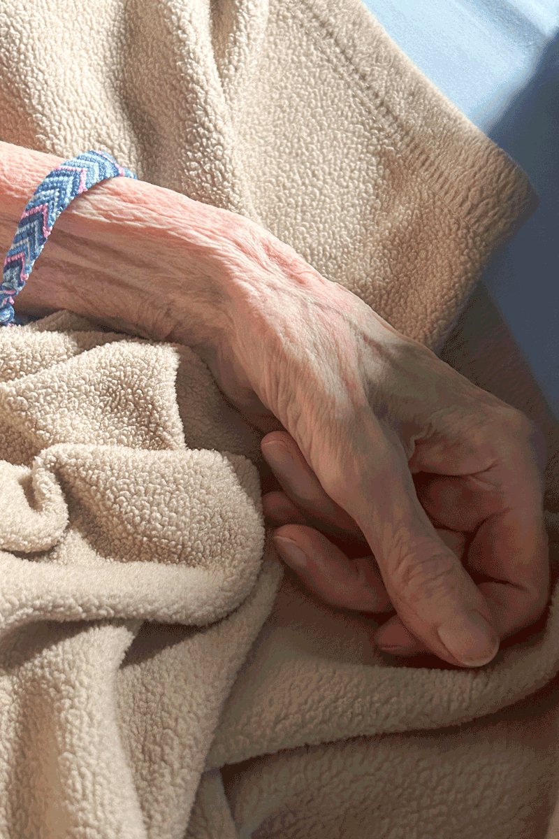 Grandmother's hand rests on the bed