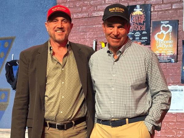 Two men stand together on stage after the announcement of the musical.