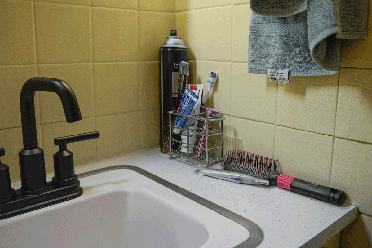 Several personal items sit by the bathroom sink