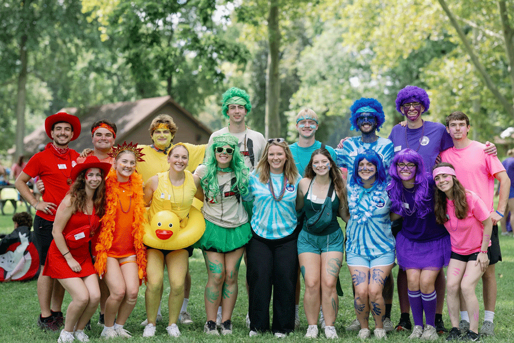 Group of student counselors pose together in rainbow colors, wigs, costumes, tutus, etc.