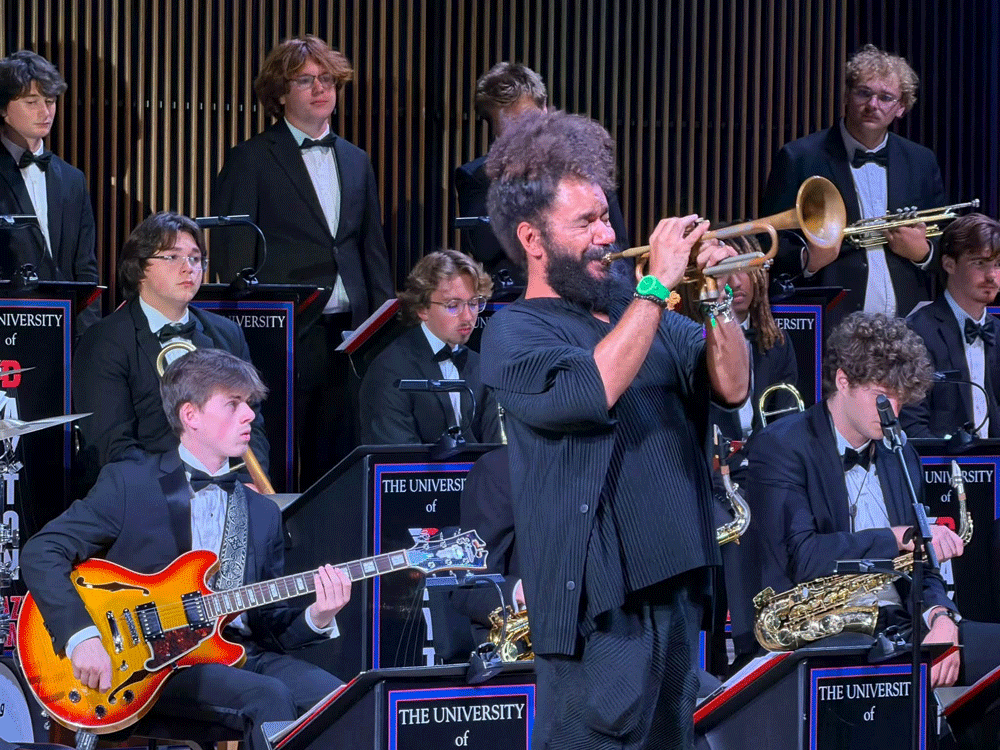 Ashlin Parker plays his trumpet on stage at the Roger Glass Center for the Arts as student musicians look on.
