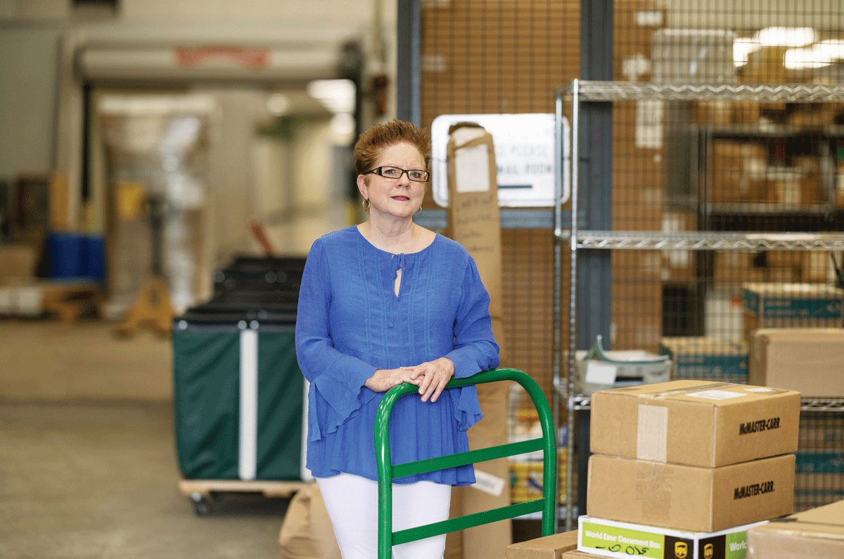 Denise Dobberstein stands with a cart in the mailroom.