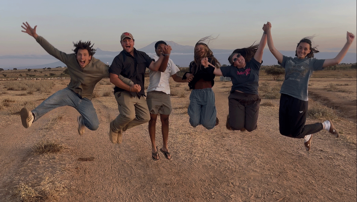 Cohort of students jumps in the air in front of mountain scenery in Kenya