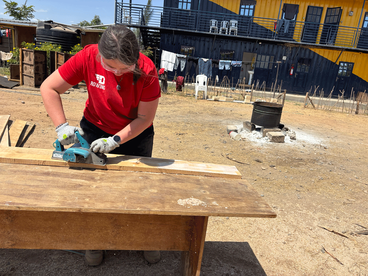 Lily Kuebler uses a saw on a piece of wood.