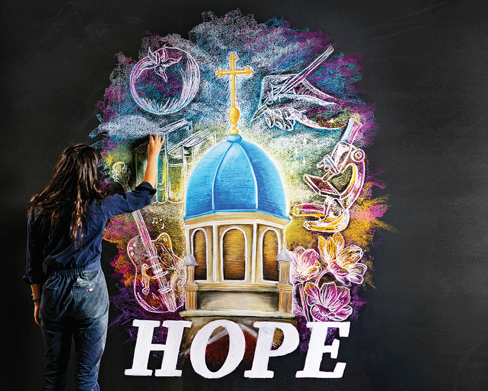Martyn stands in front of the chalkboard drawing the final lined of the Hope cover art piece.