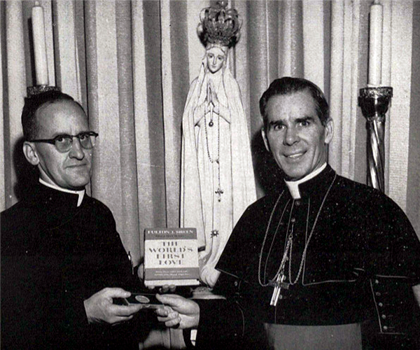 Monheim on left hands a medal to Bishop Fulton J. Sheen, right, both are looking straight ahead