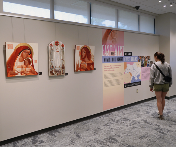 young women reading text on a long wall of icon art and exhibit graphics