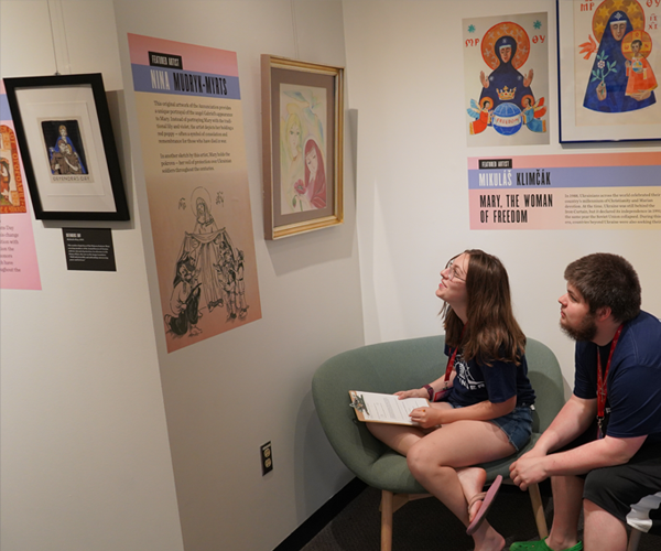 young woman and young man sitting and looking at exhibit labels and artwork