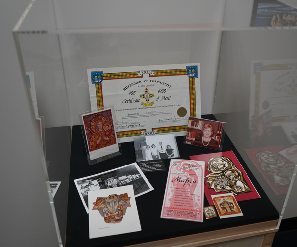glass case holding a certificate, cards, photo of Nykolyshyn and other printed items