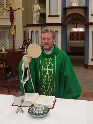 Father Bob holding up a communion host