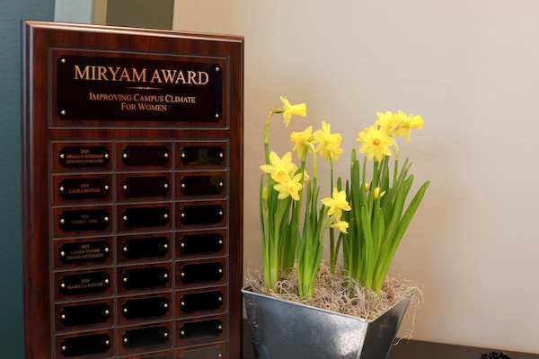 The Miryam Award plaque 2024 and yellow daffodil flowers.