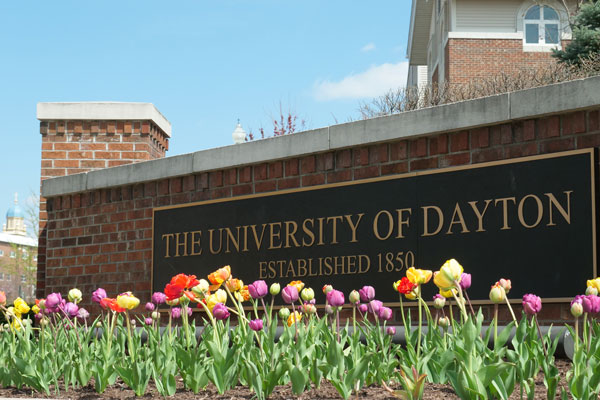 University of Dayton sign entering campus with tulips