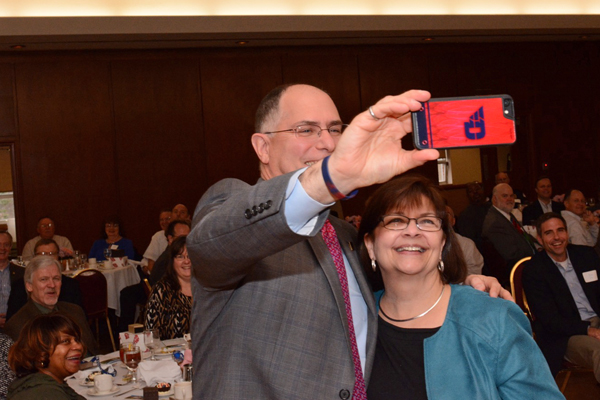 The University of Dayton President Eric Spina taking a selfie with a woman at a luncheon