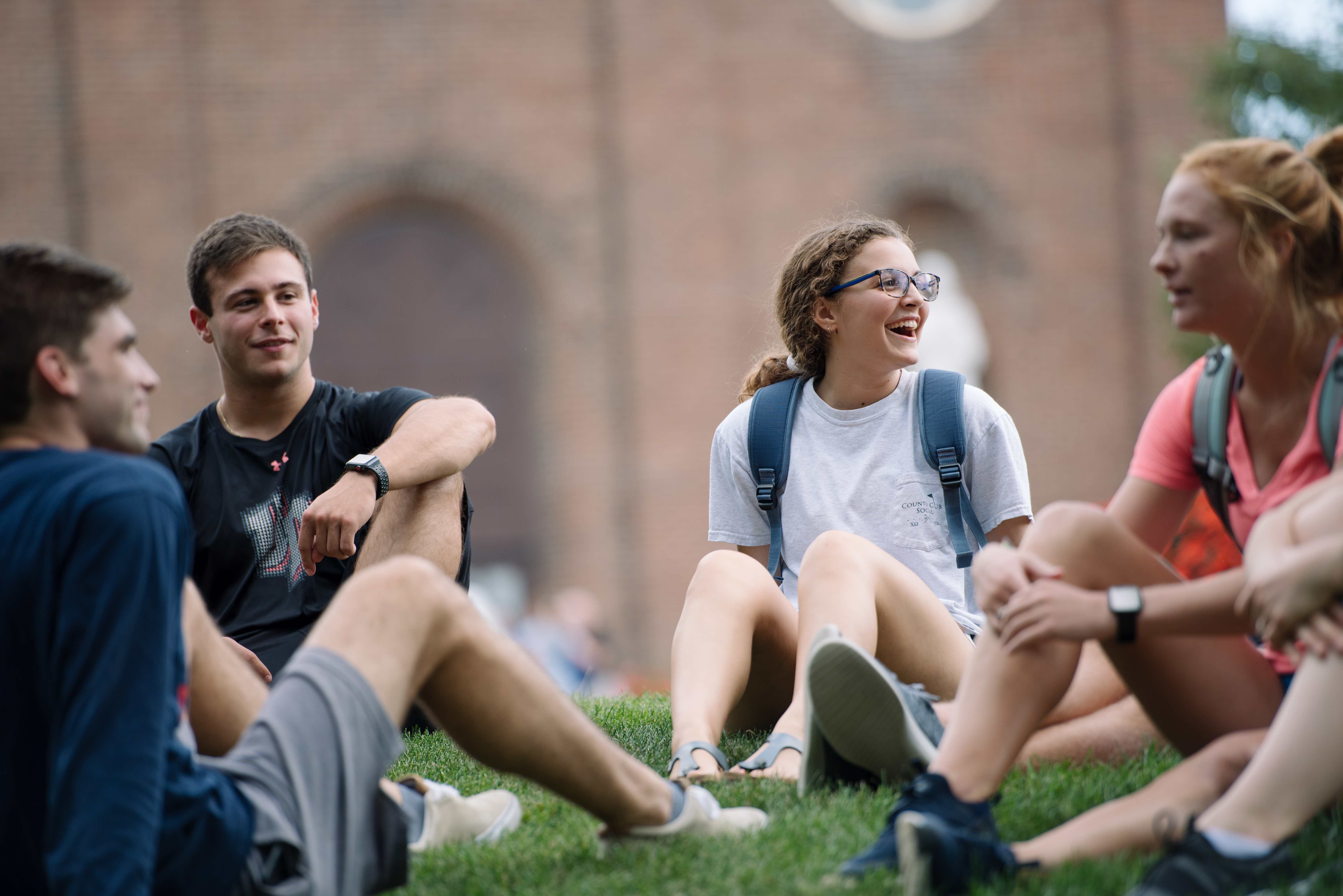 students sitting on campus lawn