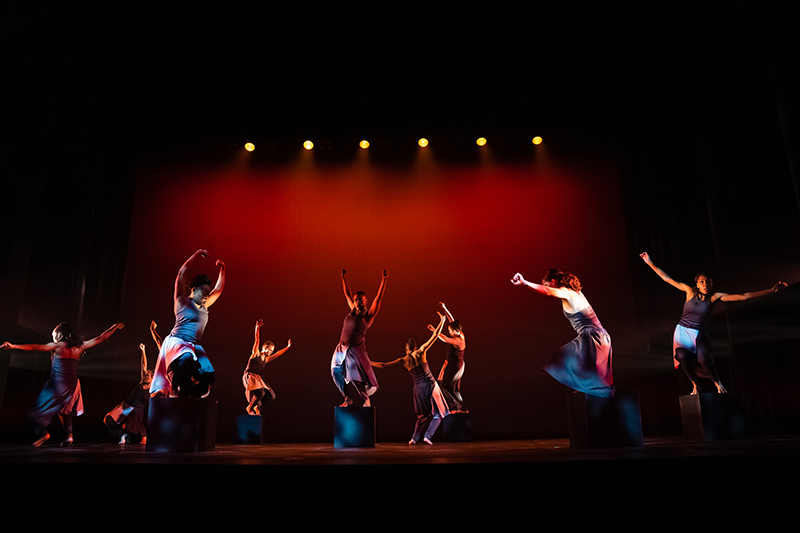 A dance performance by the University of Dayton Dance Ensemble with dancers leaping on stage
