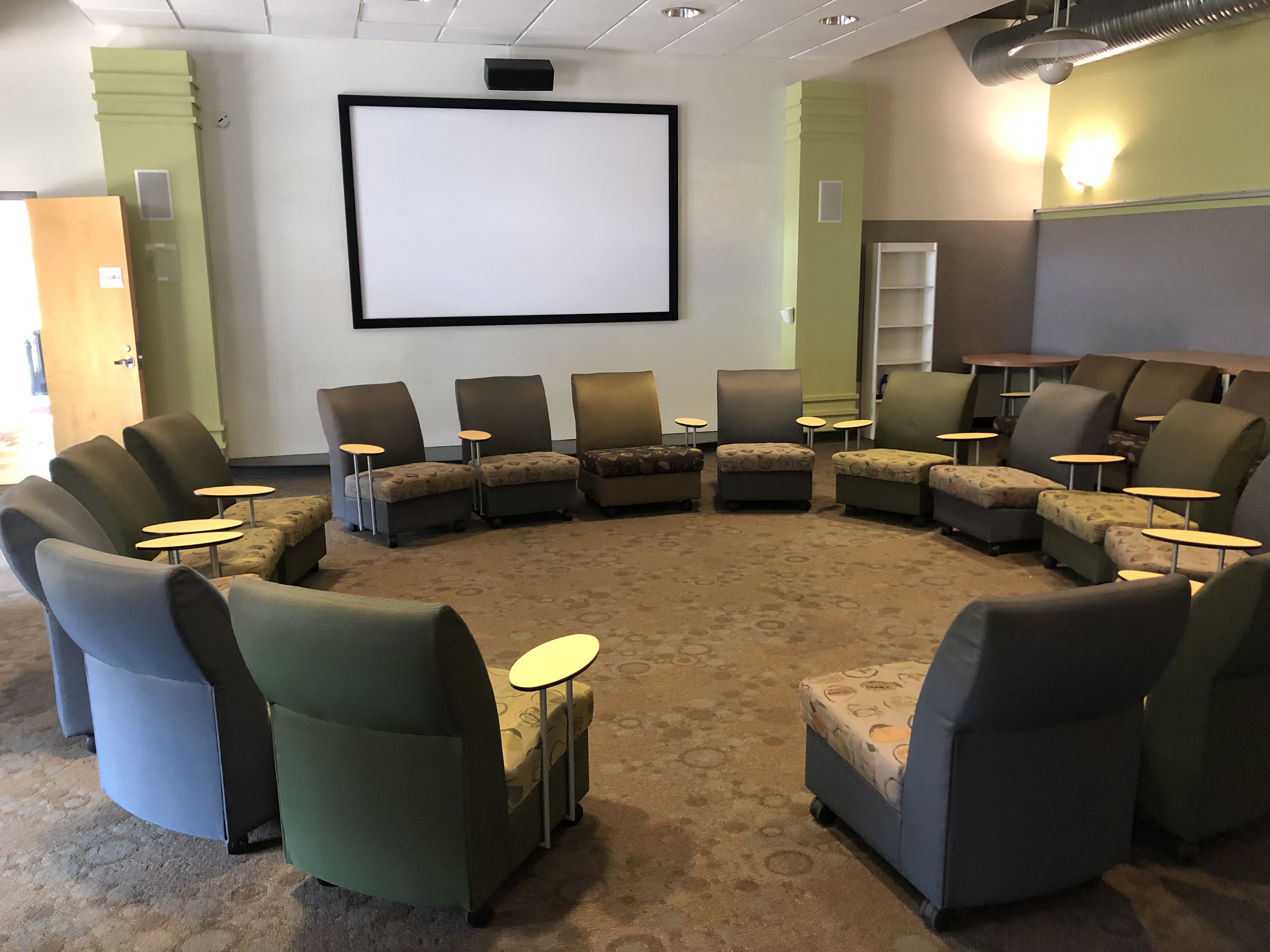 Studio B upholstered chairs with tablet desks in a circle, with projection screen