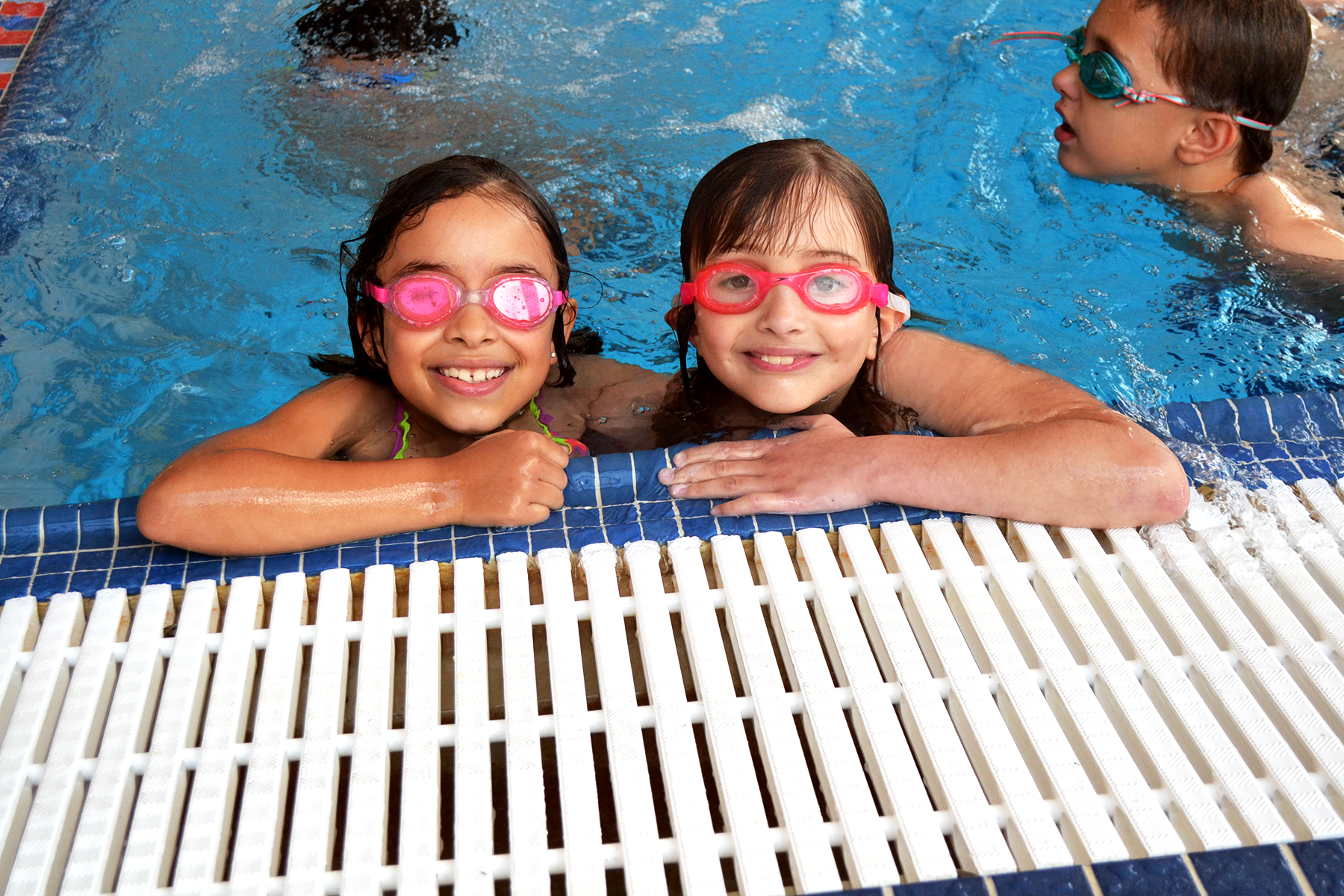 Two children in the pool smiling during their swim lesson.