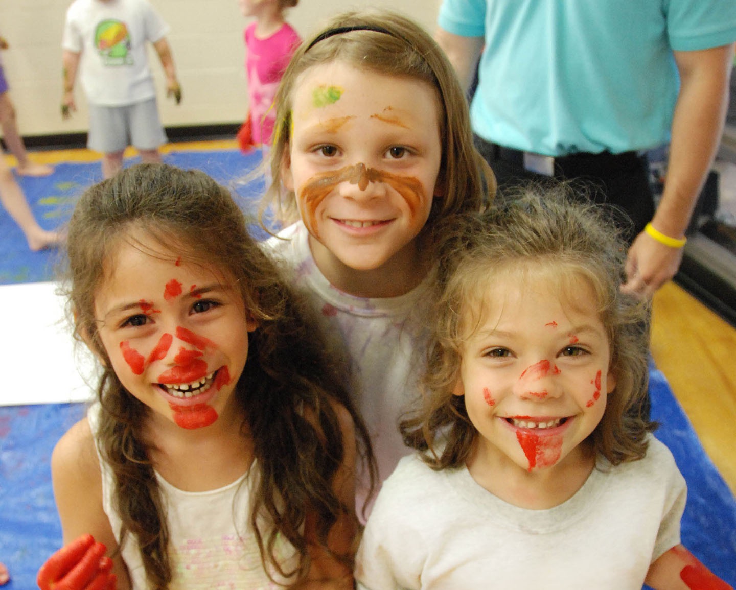${ Three RECkids campers smiling to show off their face paint. }