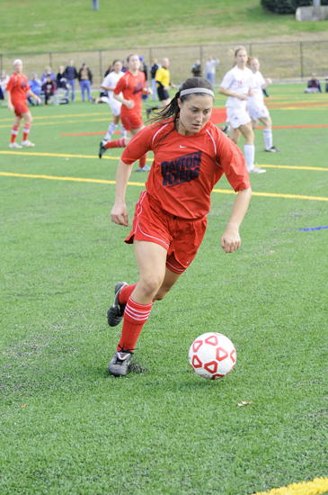 A women's club soccer player preparing to kick the soccer ball in an action shot during a game.