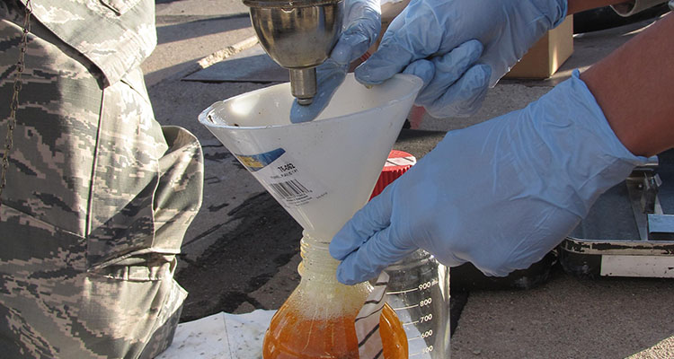 The Air Force Research Laboratory biological materials and processing research team collects fuel samples from a storage tank to analyze for potential biocontamination. (U.S. Air Force photo)