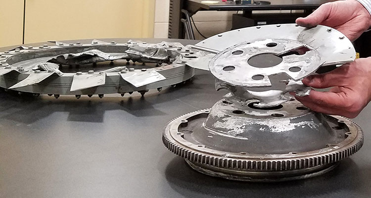 An analyst examines the broken components of a failed flywheel