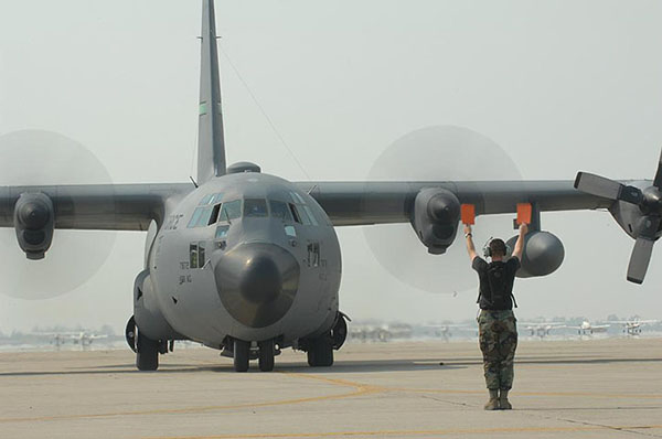 USAF ground crew personnel directs a C-130 lands that has just landed