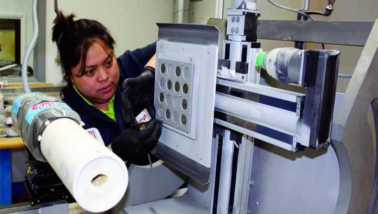 AFRL/UDRI’s Cheryl Castro installs samples for sand erosion testing in the test rig. Today’s desert sand is different from the sand used in characterization standards that have been trusted for decades. Image credit: AFRL