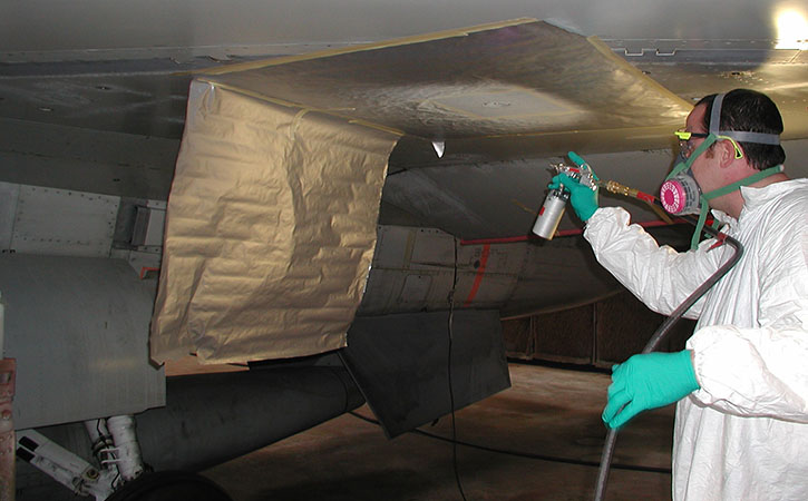 UDRI's Dan McCray applies priming material to the underside of a jet aircraft wing.