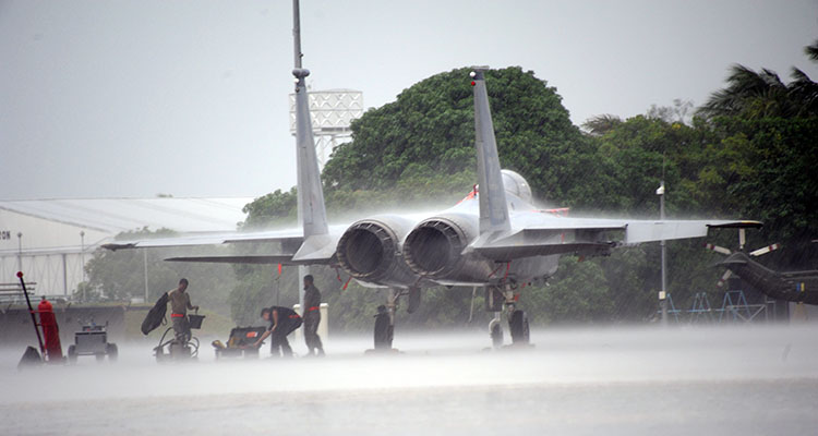 Airmen from the 67th Aircraft Maintenance Unit based at Kadena Air Base, Japan, take shelter under the wing of an F-15C during a rain shower at Cope Taufan 2012 at TUDM Butterworth, April. 3, 2012. (U.S. Air Force photo/Master Sgt. Matt Summers/Released)