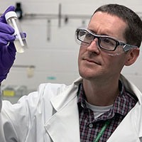 UDRI's Dr. Zachary West examines a sample of jet fuel contaminated with diesel exhaust fluid (DEF), a urea-based solution designed to reduce polluting emissions from refueling trucks.